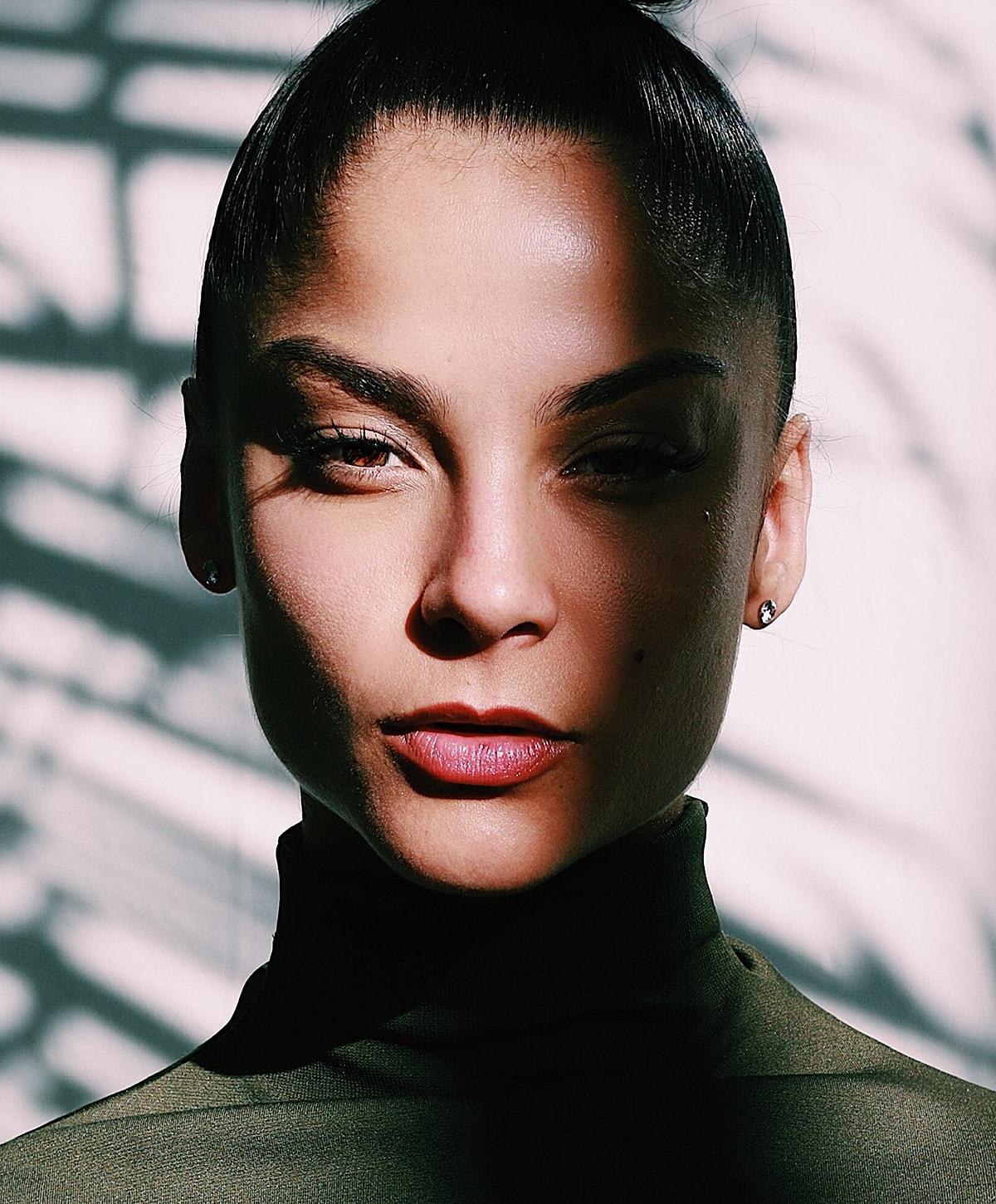 Woman with freckles softly touching her face.