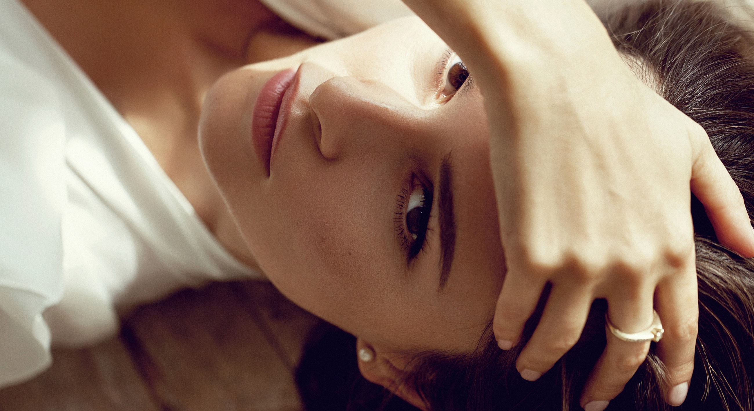 Woman lying down, hand on forehead.