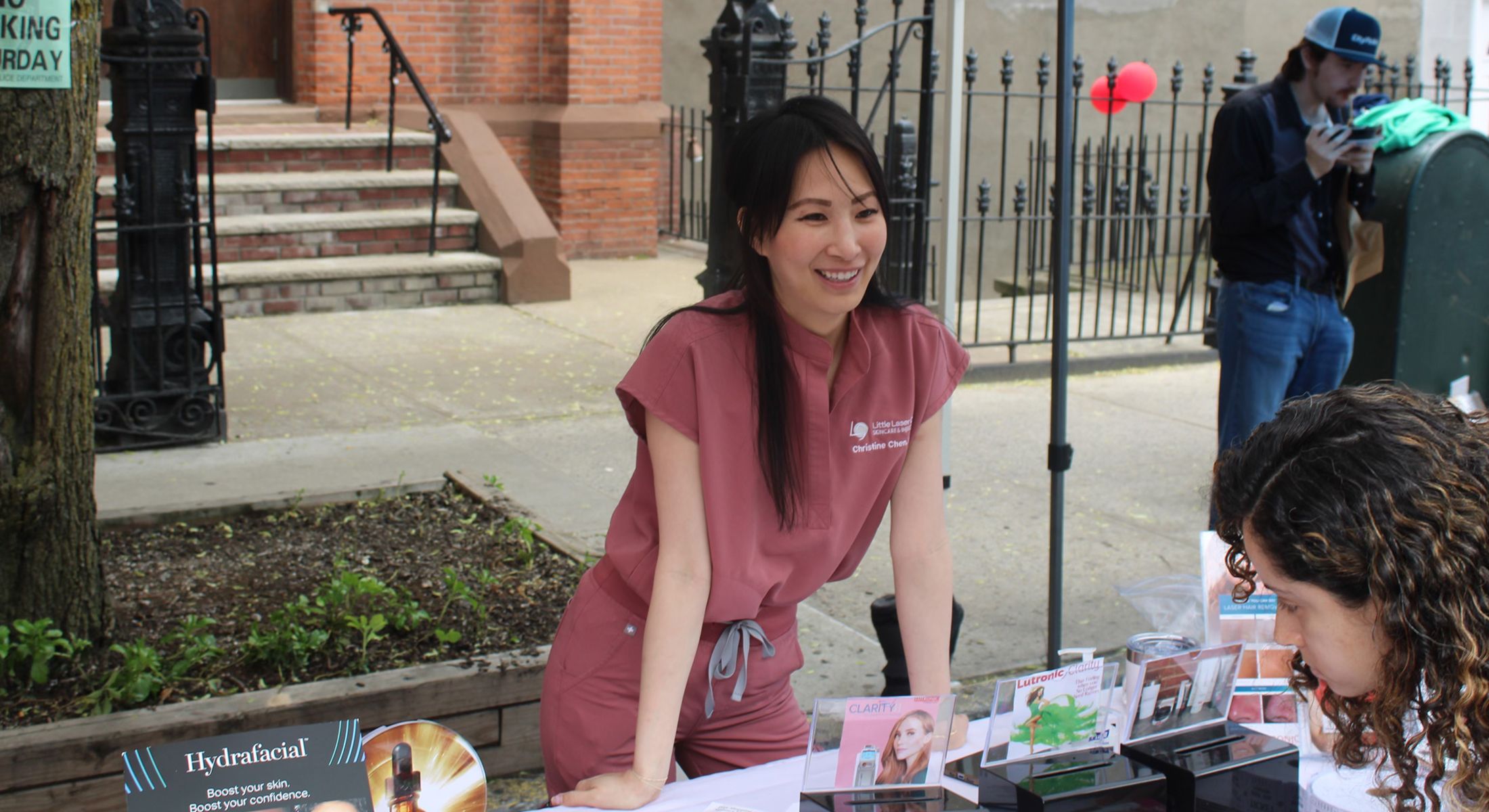 Woman promoting skincare products at outdoor event.