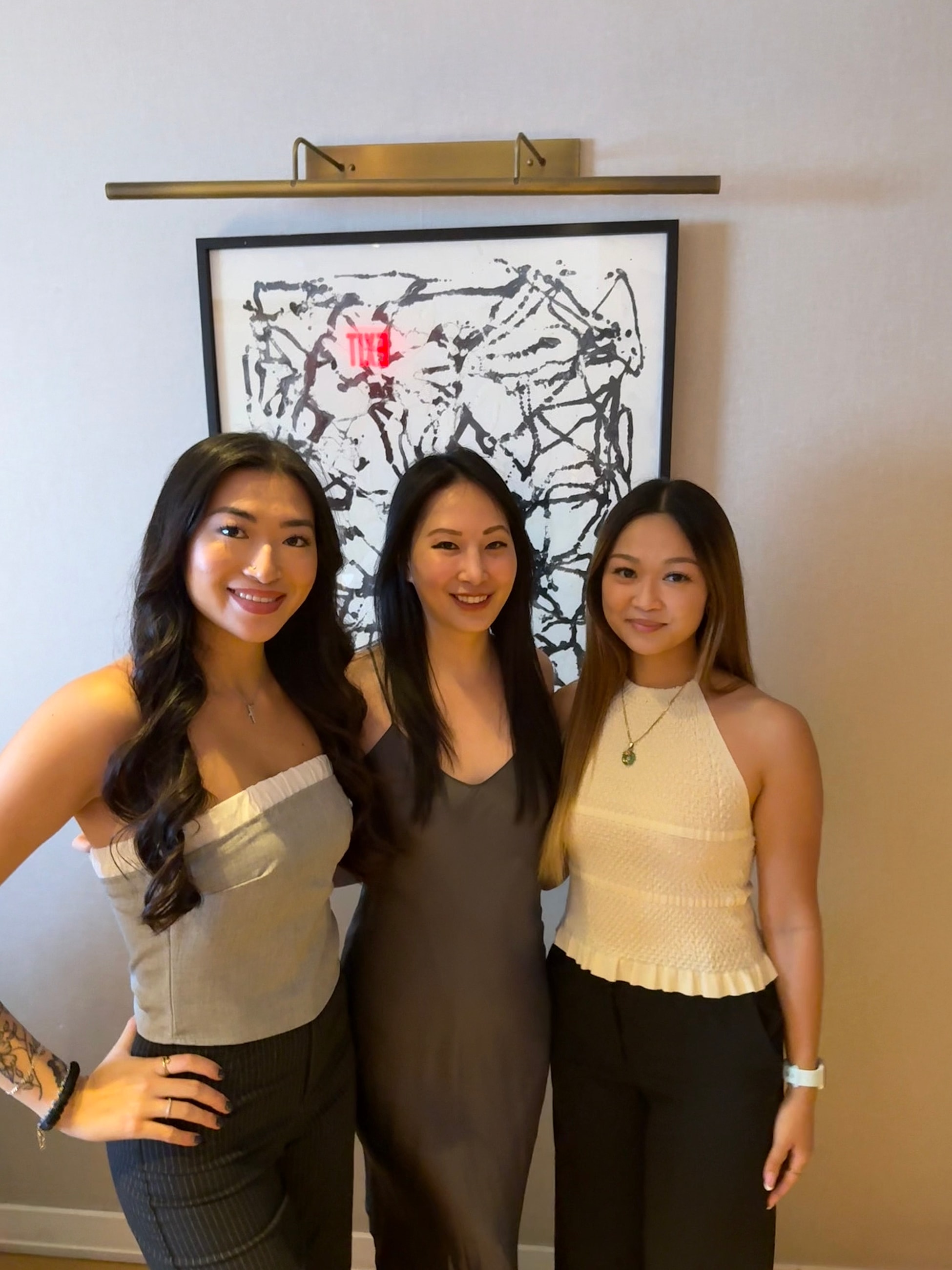 Three women posing together in elegant outfits.