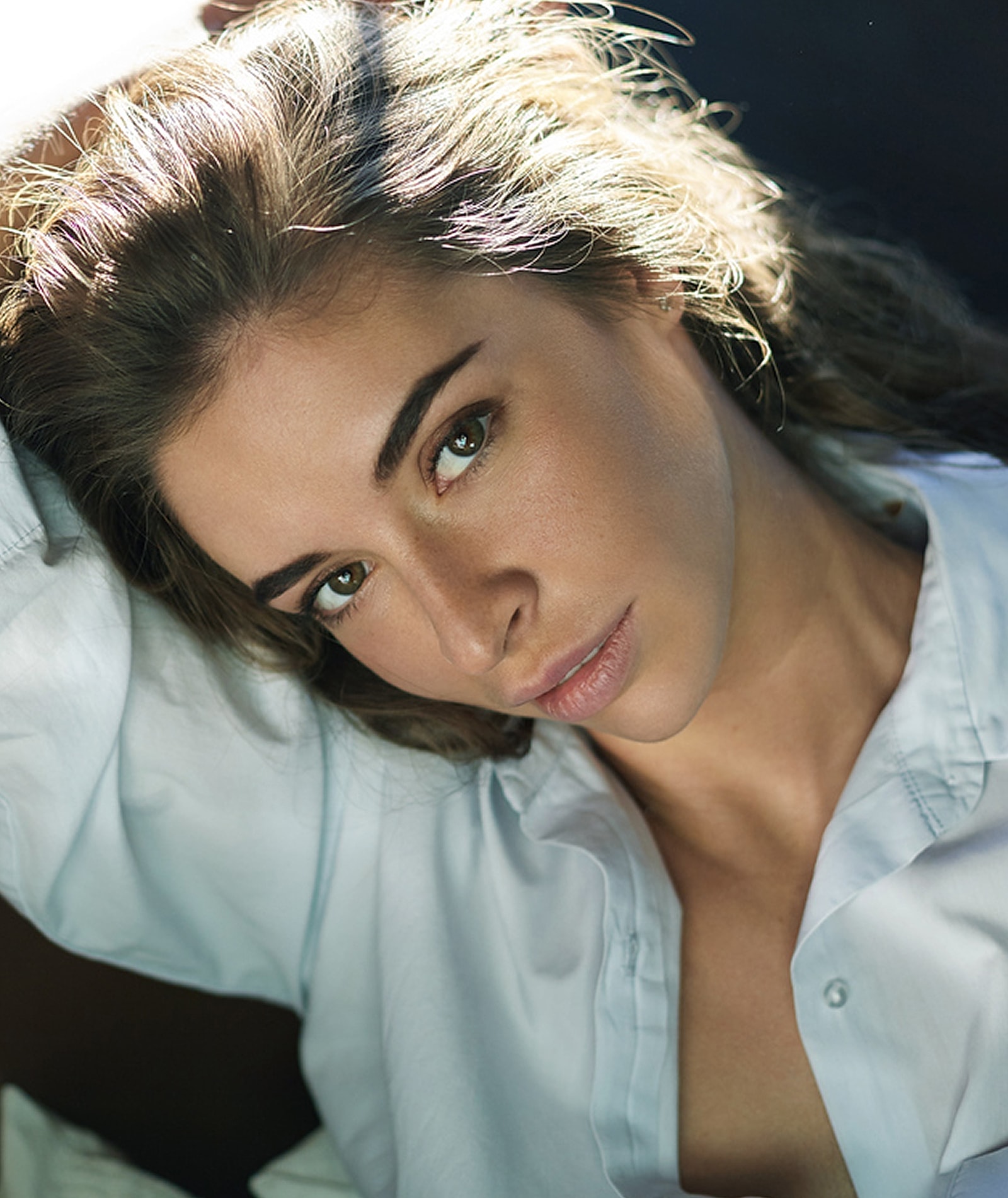 Woman with closed eyes in soft lighting.
